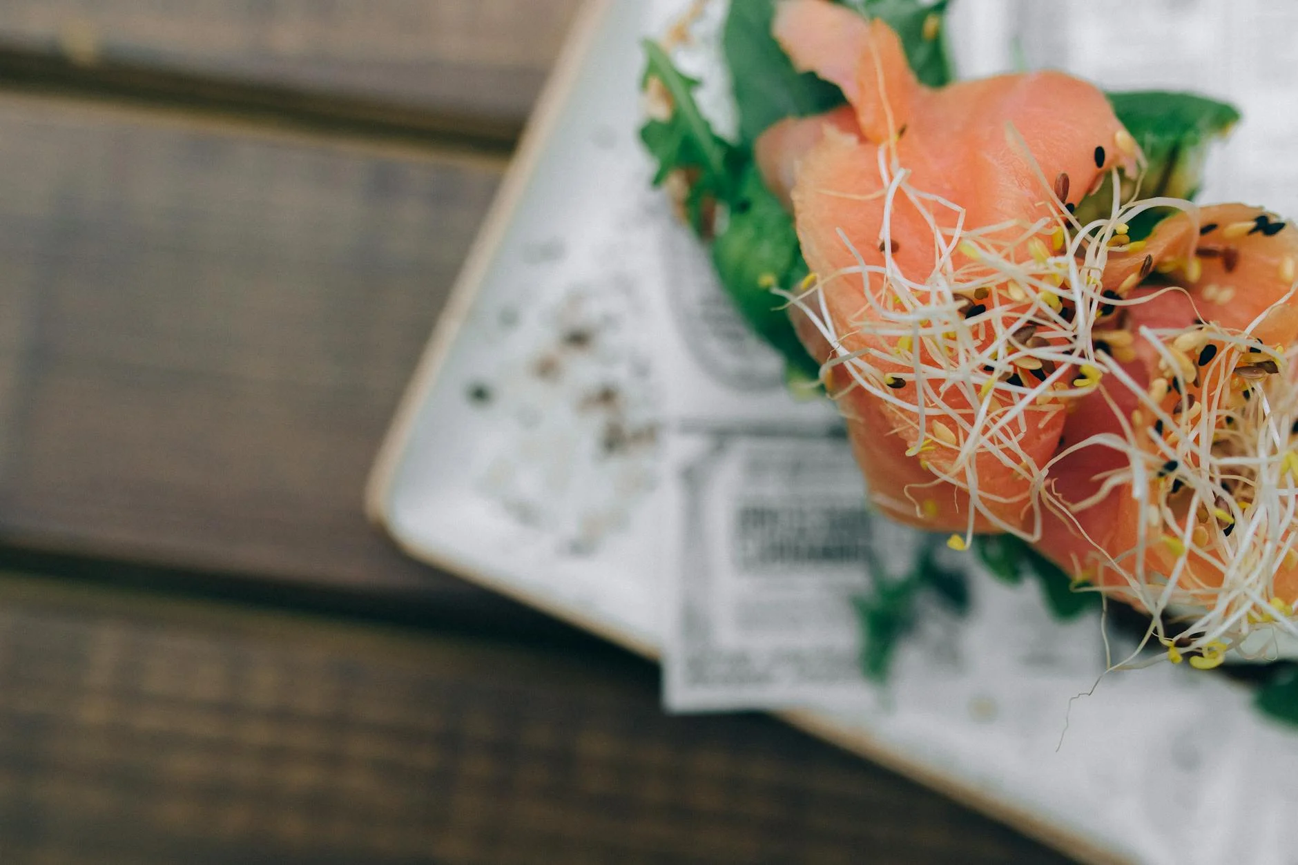 Close-up of fresh salmon sashimi garnished with sprouts, showcasing vibrant colors. — Foto: Nataliya Vaitkevich / Pexels