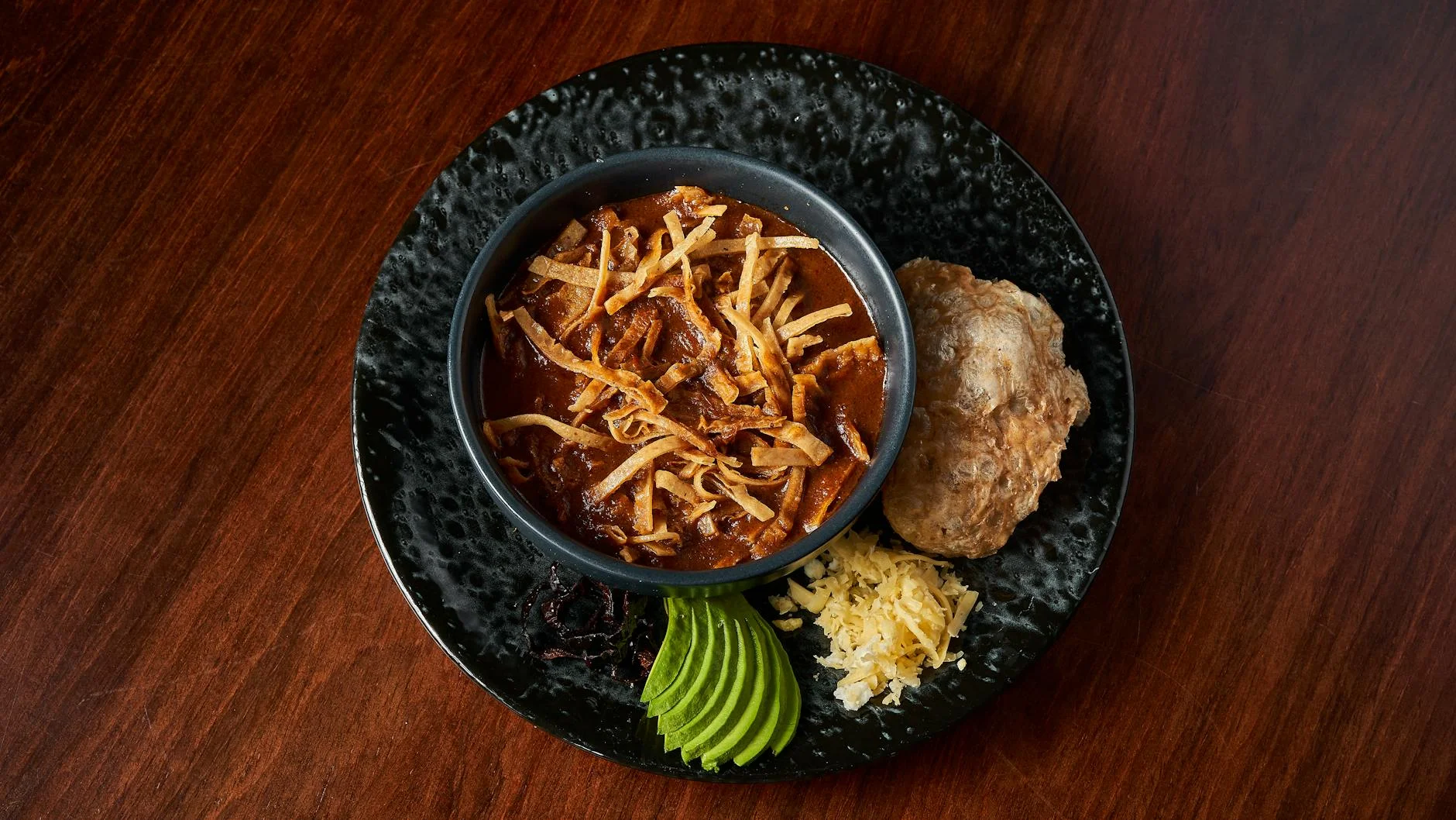 A close-up, photorealistic professional photography shot of various umami-rich vegetarian ingredients arranged artfully on a dark wooden board: dried shiitake mushrooms, ripe cherry tomatoes, a block of miso paste, nutritional yeast flakes, a piece of kombu seaweed, and roasted garlic cloves. Cinematic lighting highlights their textures and colors, creating a sense of abundance and depth. Sharp focus on the ingredients, with a soft depth of field. 8K hyper-detailed, shot on a high-end DSLR. Top view of Mexican sopa tarasca in a bowl with fresh garnishes. — Foto: Willians Huerta / Pexels