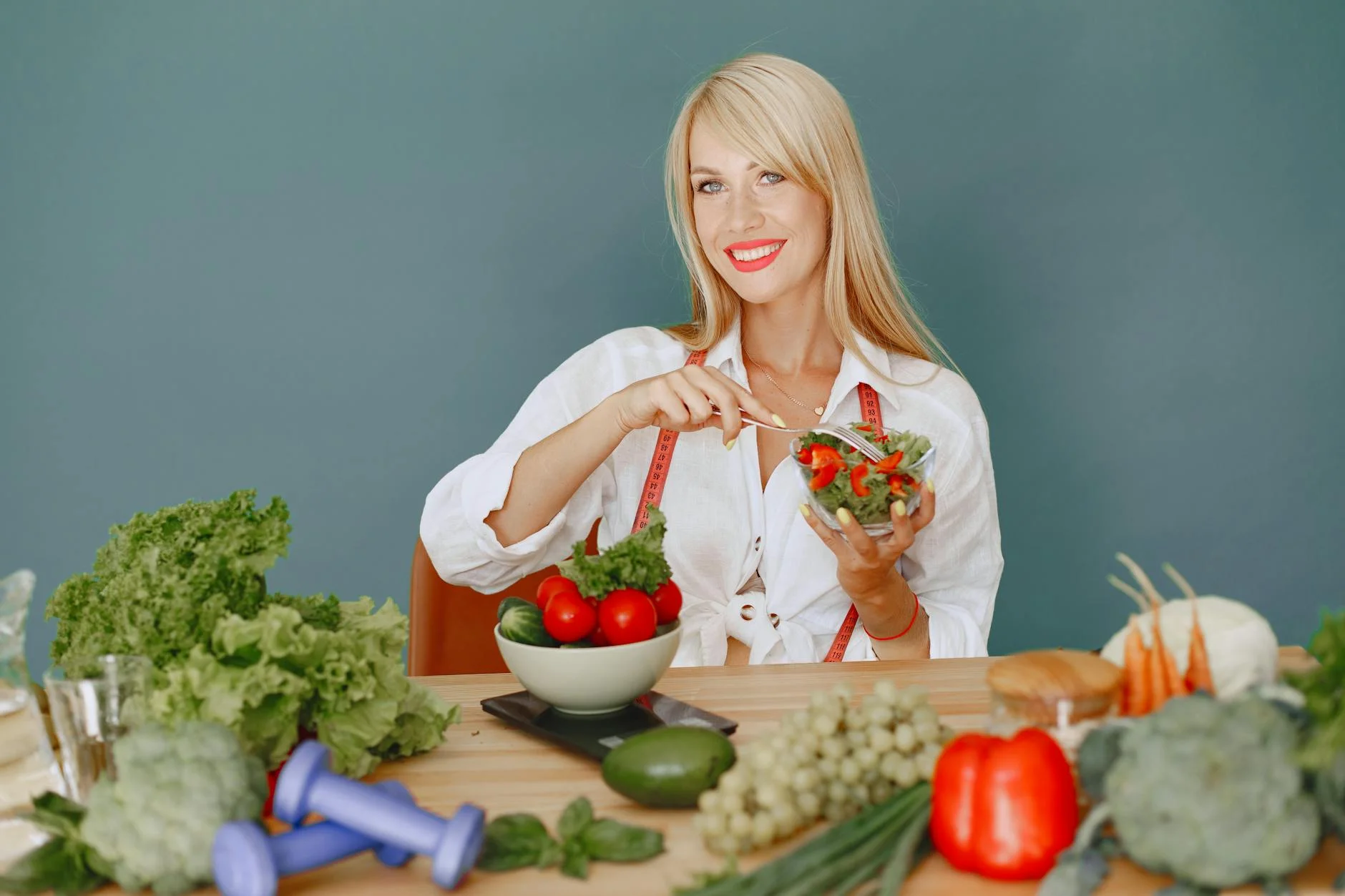 Blonde woman enjoying a fresh salad surrounded by vegetables, promoting healthy eating. — Foto: Gustavo Fring / Pexels