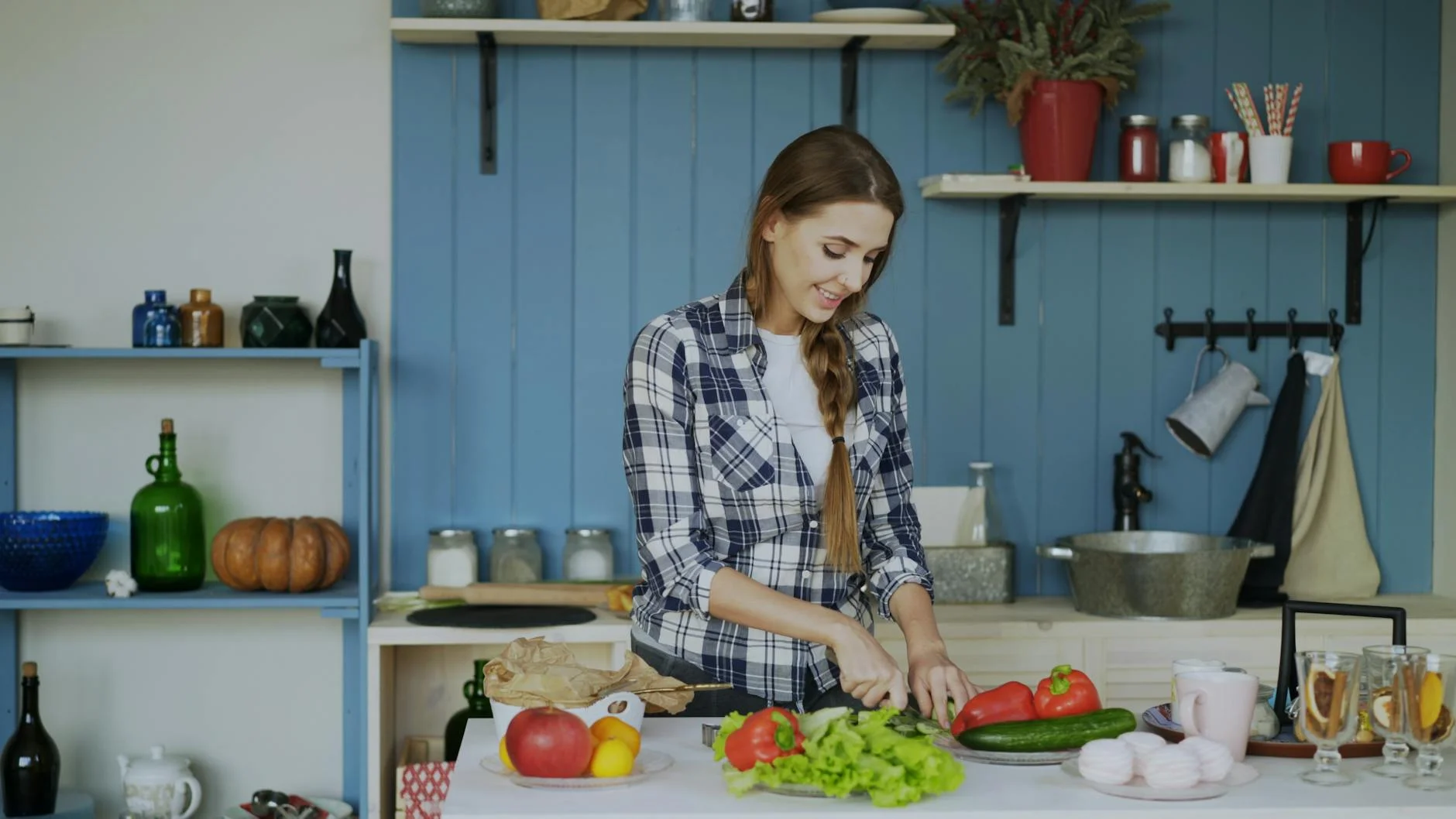 Young woman chopping vegetables in a cozy kitchen setting with fresh ingredients around. — Foto: Vitaly Gariev / Pexels