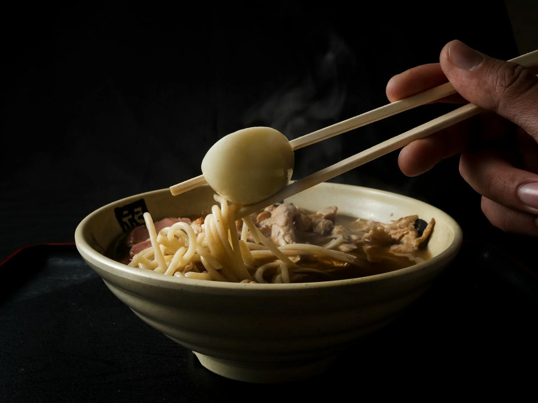 A photorealistic, professional photography shot of a variety of fresh, high-quality pork and chicken bones, meticulously arranged on a clean stainless steel surface, ready for broth making. Ingredients like kombu, dried shiitake, green onions, and ginger are artfully placed around the bones. 8K, cinematic lighting, sharp focus, depth of field, shot on a high-end DSLR. Close-up of authentic ramen noodles with boiled egg and chopsticks. Perfect for food enthusiasts. — Foto: Luis C. Tavera / Pexels
