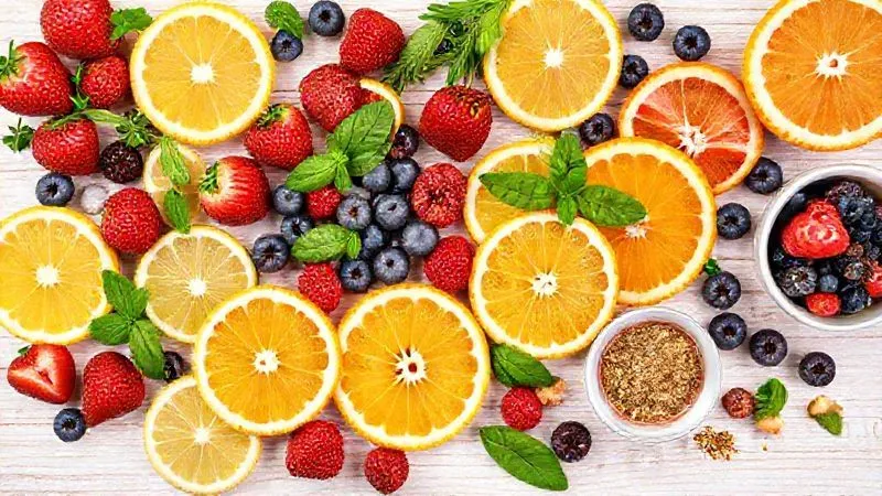 A vibrant, photorealistic spread of various ingredients for gourmet iced tea: fresh slices of lemon, lime, and orange, colorful berries (strawberries, blueberries, raspberries), sprigs of mint and basil, and small bowls of spices like ginger. All arranged artfully on a light wooden background, with soft, natural light and sharp focus on the ingredients. 8K hyper-detailed, professional photography, shot on a high-end DSLR. Evokes freshness and culinary creativity.