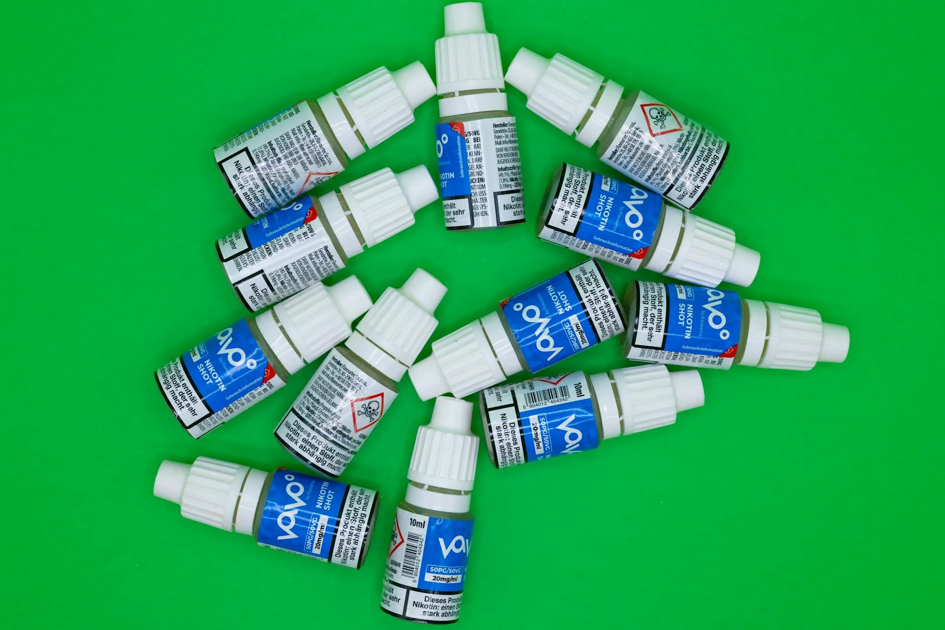 Top view of multiple nicotine vape shot bottles arranged on a green background. — Foto: Patrick / Pexels