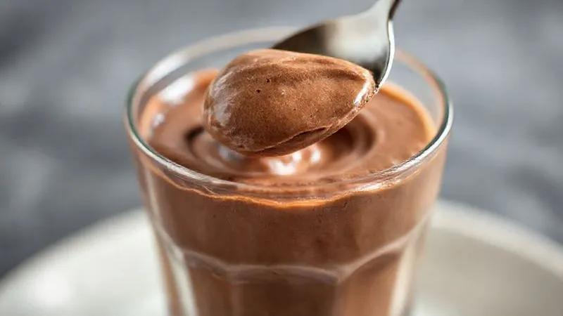 A close-up, photorealistic image of a perfectly set, airy chocolate mousse in a clear glass, with a spoon gently scooping a portion, highlighting its creamy texture. The lighting is soft and inviting, suggesting indulgence without guilt. Professional photography, 8K, cinematic lighting, sharp focus, depth of field, shot on a high-end DSLR. A close-up, photorealistic image of a perfectly set, airy chocolate mousse in a clear glass, with a spoon gently scooping a portion, highlighting its creamy texture. The lighting is soft and inviting, suggesting indulgence without guilt. Professional photography, 8K, cinematic lighting, sharp focus, depth of field, shot on a high-end DSLR.