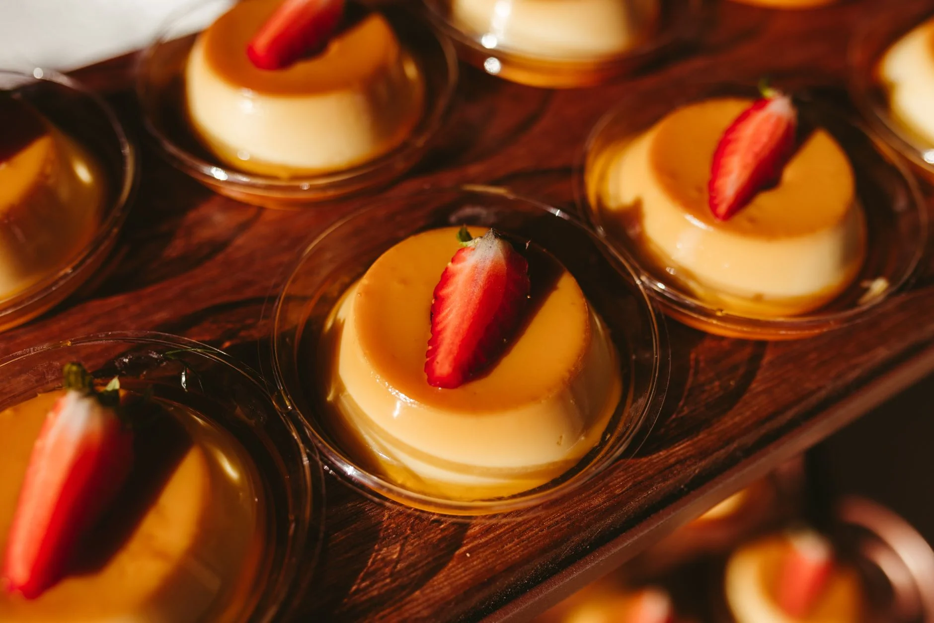 Enticing flan desserts topped with strawberries beautifully showcased on a wooden board. — Foto: Jonathan Borba / Pexels