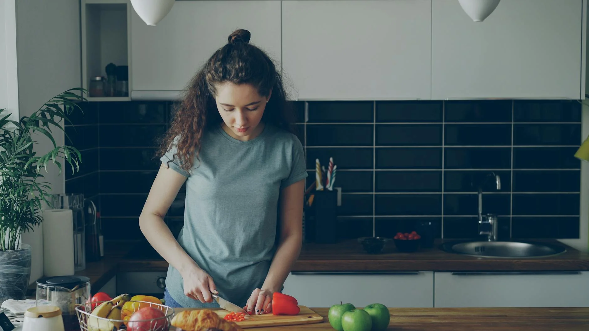 Photorealistic, professional photography, 8K, cinematic lighting, sharp focus on a detailed weekly planner or calendar, with small, colorful icons representing healthy pre-prepped snacks neatly scheduled for each day, alongside a handwritten shopping list, depth of field blurring a modern kitchen background, shot on a high-end DSLR, conveying organization and foresight. Young woman preparing food in a modern kitchen setting, cutting vegetables. — Foto: Vitaly Gariev / Pexels
