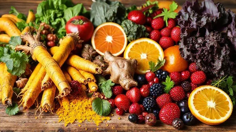 A photorealistic, professional photography image of a vibrant, colorful display of fresh anti-inflammatory ingredients: bright yellow turmeric roots, fiery red ginger, dark green spinach and kale, various red and purple berries, and bright citrus fruits. All are arranged organically on a rustic wooden surface, with gentle cinematic lighting highlighting their textures and freshness. Sharp focus on the ingredients in the foreground, with a soft depth of field. 8K hyper-detailed, shot on a high-end DSLR, symbolizing nature's pharmacy.