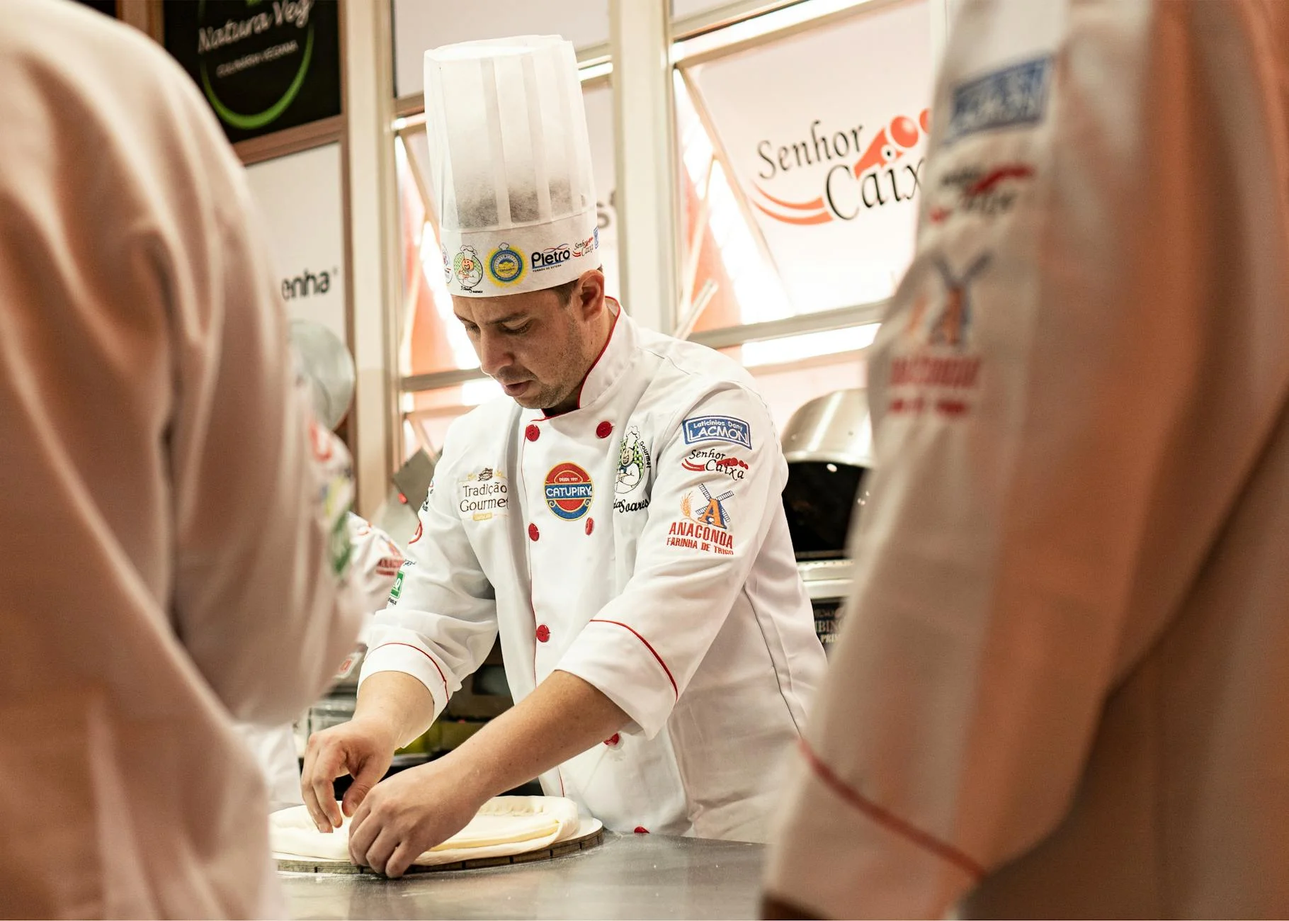 A chef in uniform preparing dough in a professional kitchen setting. — Foto: Mario  Schafer / Pexels