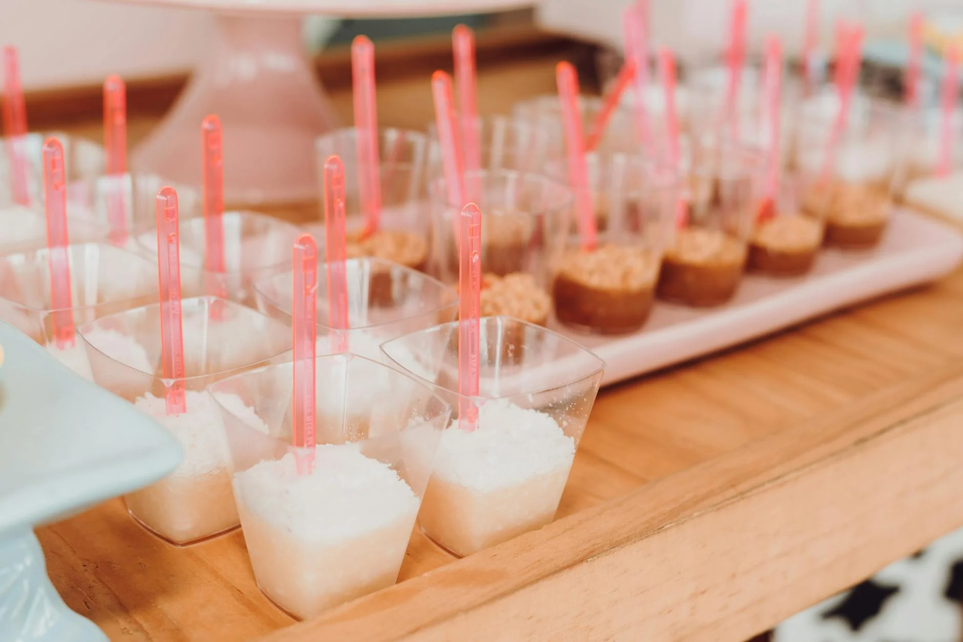 Array of mini desserts in transparent cups with pink spoons, perfect for catering events. — Foto: SAULO LEITE / Pexels