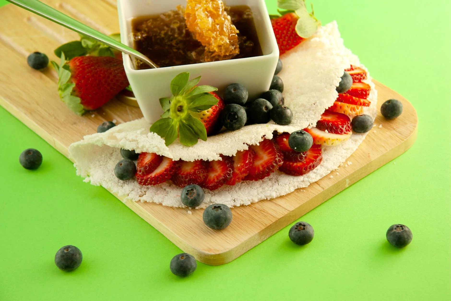 A photorealistic overhead shot of a colorful array of fiber-rich ingredients, including a bowl of chia seeds, flaxseeds, fresh spinach leaves, sliced avocado, and berries, artfully arranged around a small, empty tapioca pan. Cinematic lighting, sharp focus, vibrant colors, 8K, professional photography. Tapioca wrap with strawberries, blueberries, and honeycomb makes a vibrant snack. — Foto: Karen Laårk Boshoff / Pexels