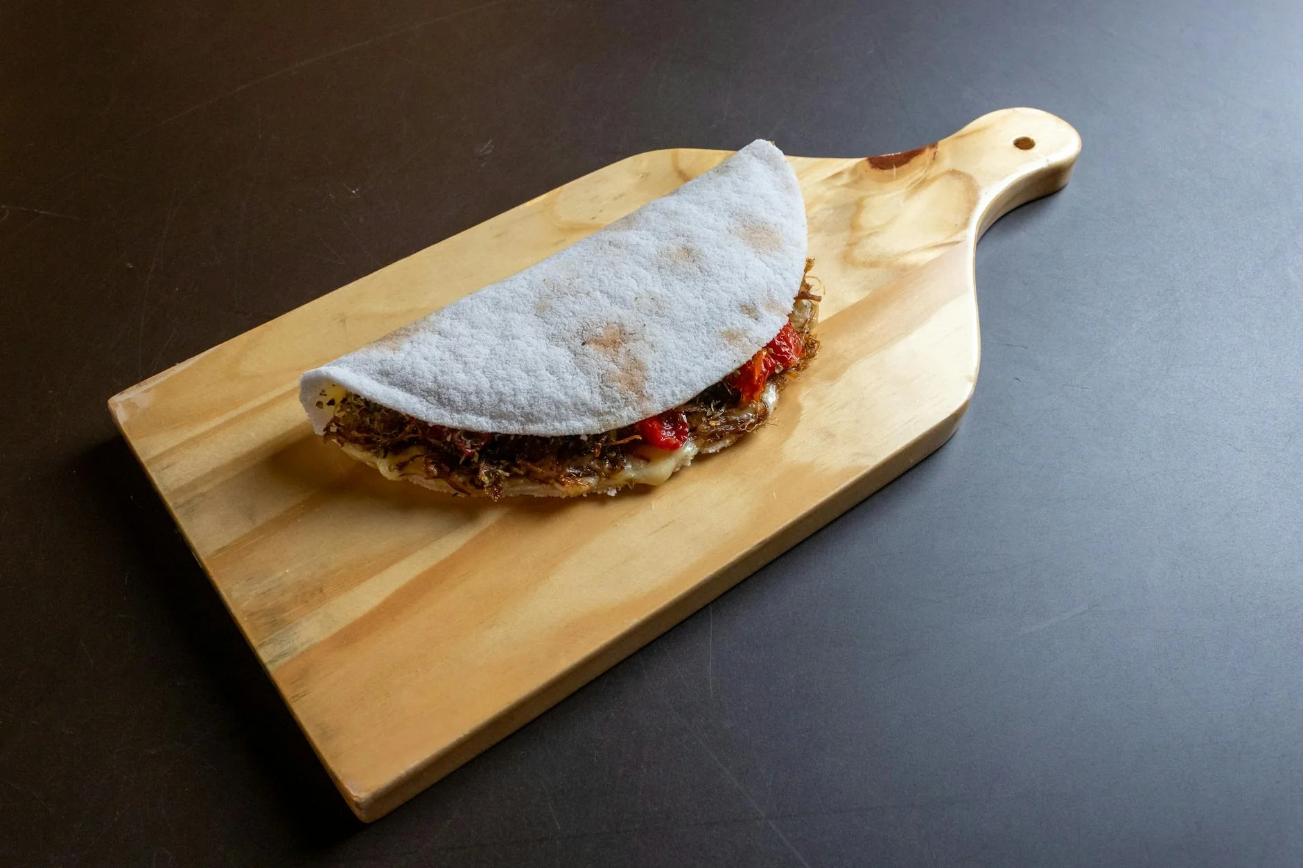 A flavorful tapioca wrap filled with ingredients displayed on a wooden board. — Foto: Hiure Gomes Fernandes / Pexels